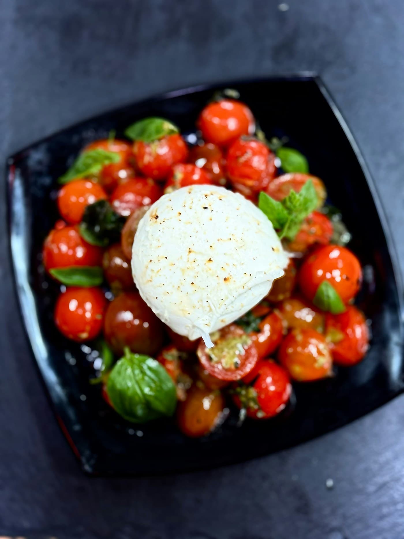 Burrata au centre d'une assiette de tomates cerises et de basilic